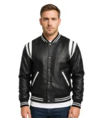 A man wearing a black leather varsity jacket with white stripe detailing on the cuffs, hem, and shoulder seam, set against a white background.