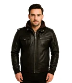A man wearing a dark brown leather hooded bomber jacket featuring a built-in fabric hood, chest zipper pockets, and shoulder epaulets.
