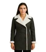 A woman wearing a premium black leather shearling coat with a thick, lined collar and matching cuffs.