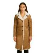 A woman modeling a luxurious women's tan shearling coat featuring a smooth camel-toned leather exterior and a plush ivory wool lining.