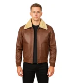 A man wearing a high-quality brown leather bomber jacket featuring a cream-colored fur collar and ribbed cuffs, set against a white background.