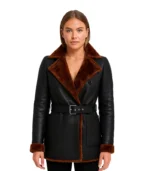 A sleek black leather belted coat featuring a thick, contrasting white or black shearling lining visible at the collar, cuffs, and hem.