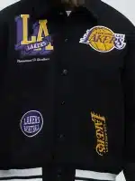 Close-up of chest patches on black Lakers varsity jacket showing clean stitching and sharp detailing.